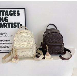 Detail of cream and brown mini backpacks with bear patterns and fuzzy eye charms
