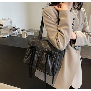 Detail of dark grey retro tote bag featuring stylish pleated texture and ribbon bow design
