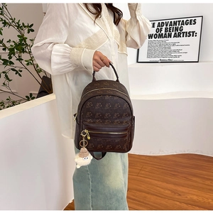 Brown mini backpack featuring bear prints and plush charm shown in hand