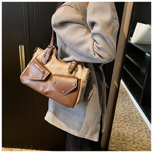 Detail der braunen Vintage-Tasche mit Retro-Nähten und dekorativen Metallreißverschlusstaschen