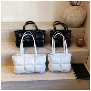 Quilted down-style tote bags in black and white on marble steps showcasing sizes