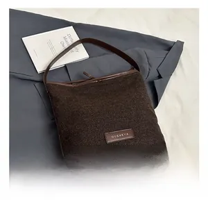 Detail showing deep brown tweed texture and leather branding on large capacity shoulder bag