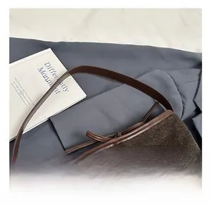 Detail of brown woven bucket bag with leather accents and a decorative bow tie