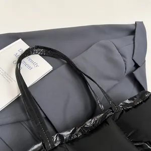 Detail of wide comfortable handle and glossy wrinkled texture on black tote bag