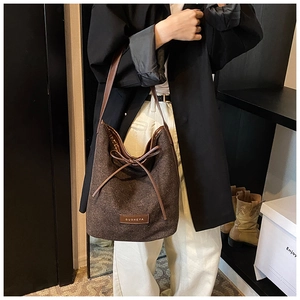 Detail of dark brown hobo bag with leather strap, bow tie, and brand label