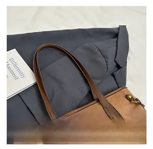 Détails du sac cabas en daim marron avec anses en cuir et breloque baseball