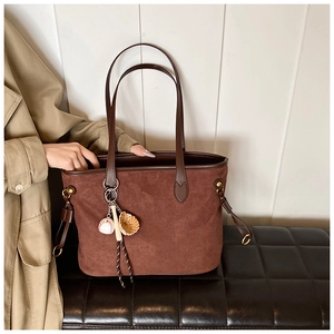 Détail d'un sac cabas en daim marron avec des breloques de baseball et gant sur le côté