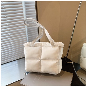 Close-up of white quilted puffer tote bag with puffy texture on a decorative book
