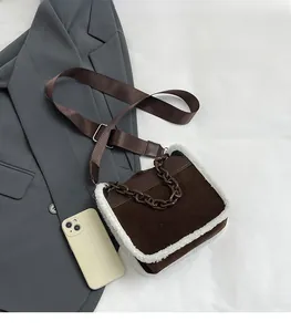 Close-up of brown suede crossbody bag with white faux fur trim and chunky plastic chain