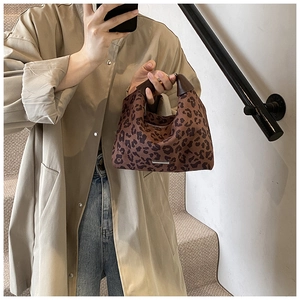 Detailansicht der stylischen Umhängetasche mit Leopardenmuster und Ledergriffen mit Metallleiste