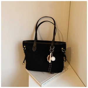 Détail du sac cabas en toile noire avec pendentif baseball et poignée en cuir chic