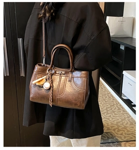 Detail of vintage brown tote bag with metal buckle and decorative tassel pendant