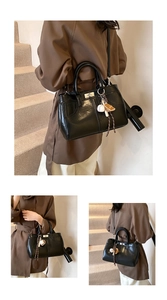 Close-up of black glossy leather bag with curved stitching and baseball charm detail