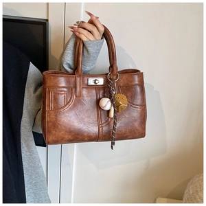 Detail of vintage brown leather handbag featuring pocket stitching and metallic swivel lock