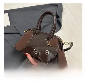 Detail of brown fashion pillow bag with contrast stitching and small coin purse charm