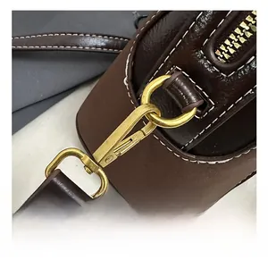 Detailed macro view of matte gold hardware, lobster clasp, and stitching on leather bag