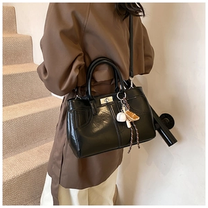 Detail of vintage brown leather tote bag with baseball glove pendant and metal twist lock