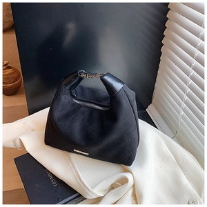 Makroaufnahme einer schwarzen Wildleder-Handtasche mit Ledergriff und Silberbeschlägen