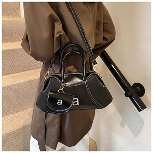 Macro detail of black leather Boston bag with white stitching and signature 'a' logo charm