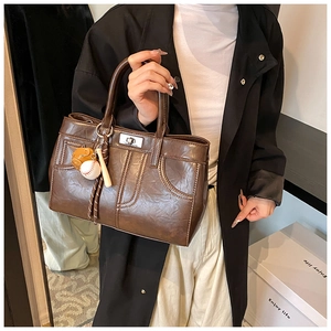 Detail of vintage dark brown faux leather handbag with silver twist lock and sports charm