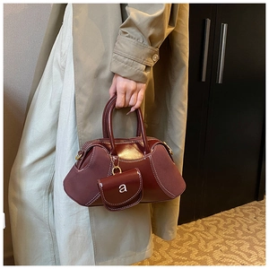 Detailed shot of burgundy stitching and mini coin purse attachment on the handbag