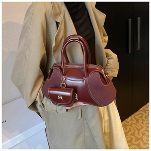 Detail of burgundy matte leather handbag with mini charm bag and double handles