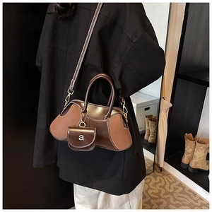 Detail of vintage matte brown crossbody bag with miniature hanging pouch attachment