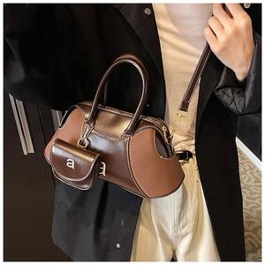 Detail of Boston bag with brown gloss leather stitching and decorative charm