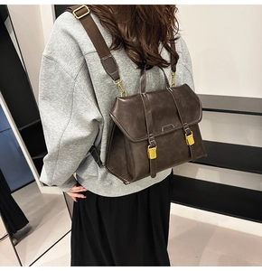 Side view of dark brown vintage faux leather backpack with gold buckles on model
