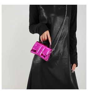 Hot pink metallic mini crossbody bag with silver chain strap on black dress background