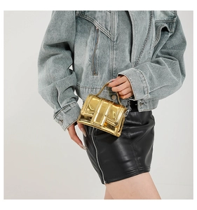 Detail of mini gold mirror finish crossbody bag with silver chain strap and top handle