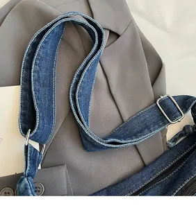 Detail of adjustable denim shoulder strap with silver metal buckle and white stitching