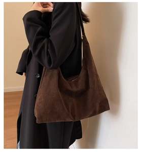Detailed texture of brown suede tote bag worn over a black winter wool coat