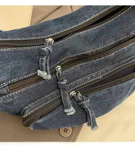 Close-up of durable denim messenger bag featuring triple metal zippers and fringe details