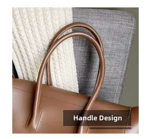 Detailed macro view of the brown leather tote bag handle with refined stitching craftsmanship