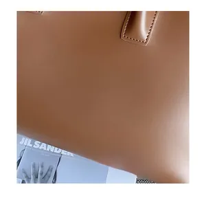 Detail of smooth brown leather texture and even stitching on a minimalist handbag
