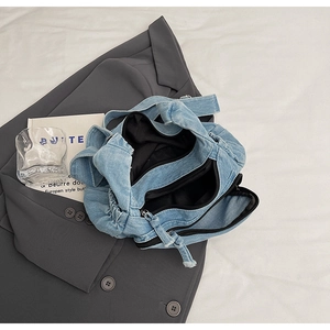 Detail view of light blue denim tote bag with multiple zip pockets and spacious interior