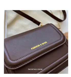 Detailaufnahme der dunkelbraunen Leder-Umhängetasche mit goldenem Fashion & Bags-Druck