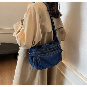 Detail of blue denim hobo bag showing multi-zipper compartments and large capacity