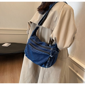 Side view of a vintage dark blue denim messenger bag with double front zip pockets