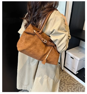 Detailed side view of a large brown suede tote bag with smooth leather strap for work