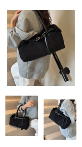 Detail of matte black tote bag showing adjustable straps and metallic hardware accents