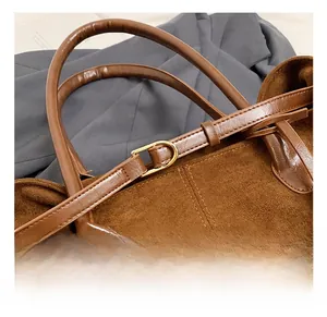 Detail of golden metal buckle on brown suede tote bag with leather straps and suit background