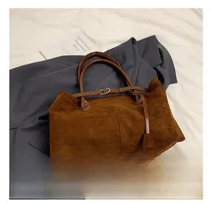 Detailed view of dark brown faux suede tote bag with decorative straps and stitching
