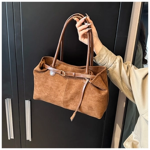 Close-up of brown suede tote bag featuring leather straps and metallic buckle detail