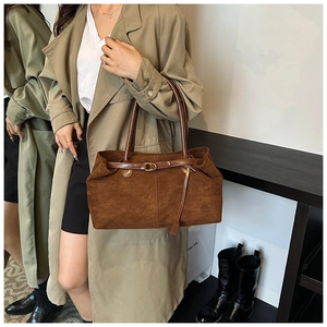 Brown suede tote bag side view on model wearing a trench coat in a cozy studio
