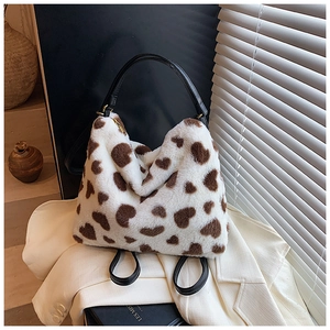 Gros plan d'un sac cabas en fausse fourrure blanche avec motifs cœurs bruns et anses noires