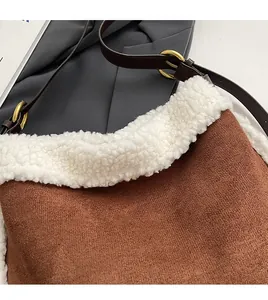 Close-up of brown suede tote with white faux shearling trim and adjustable leather strap