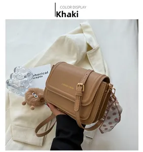 Khaki Leder Umhängetasche mit Klappe, Zierschnalle und flauschigem Anhänger im Detail