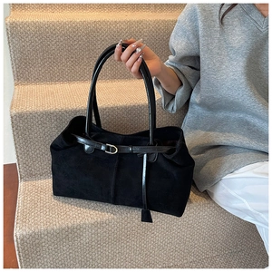 Detail of a large black suede tote bag with matte texture and decorative metal buckle strap